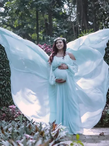 A different take on the "angel wings" pose, this time with a floral crown for a bohemian touch. The light and airy fabric of the blue gown is perfect for creating these whimsical, flying effects.