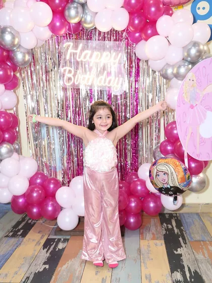 The birthday girl with her arms outstretched, soaking in the joy of her Barbie-themed party.