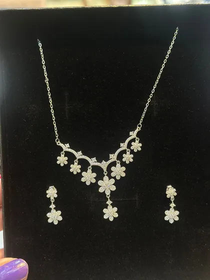 This is a delicate silver 925 necklace and earring set, featuring a floral design with sparkling stones. It's a lightweight and elegant choice for parties or as a special gift.