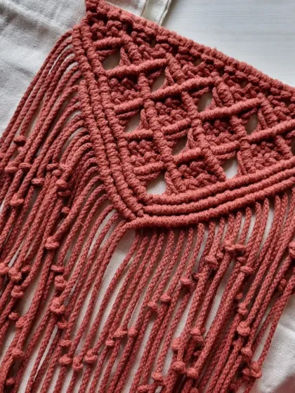 The detailed, V-shaped macrame pattern on this tote bag is a real eye-catcher. The dusty rose color is soft and versatile.