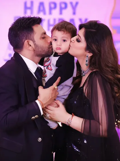 A loving family photo from a birthday party, with the birthday boy getting kisses from mom and dad.