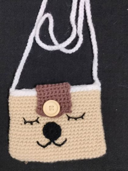 Another one of my cute handmade bags for kids. This one has a sleepy little face on it. It is made with beige yarn and has a simple strap for easy carrying.