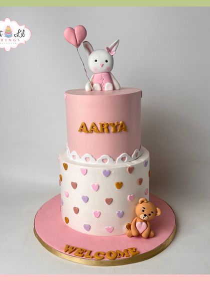 A sweet welcome for baby Aarya. This two-tiered pink and white cake is decorated with hearts and topped with an adorable bunny holding a heart balloon.