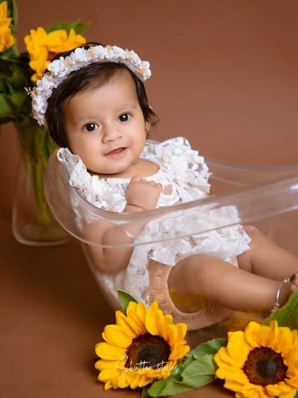 Another adorable shot of the baby girl in the transparent tub, smiling sweetly for the camera.