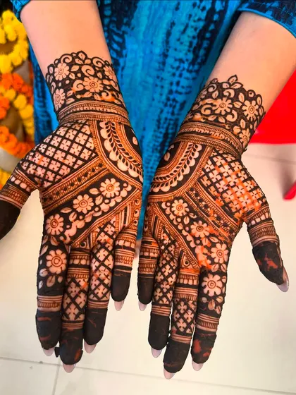 A beautiful example of symmetrical bridal mehendi. Both hands are adorned with a dense floral and jaal pattern, complete with darkened fingertips for a traditional finish.