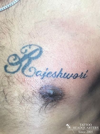 A chest tattoo of the name "Rajeshwori" with a large, decorative initial 'R'.