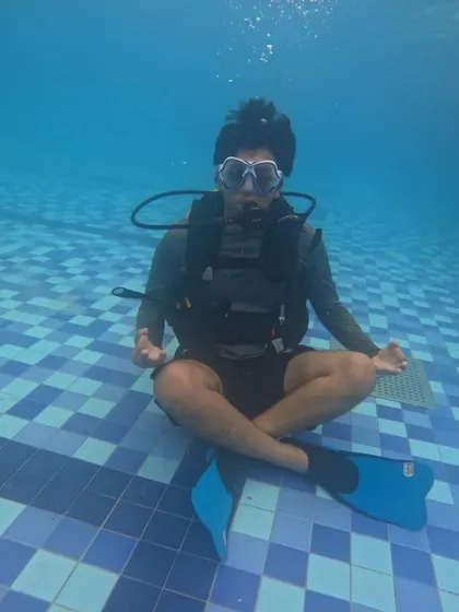 Find your moment of calm beneath the surface. This shot from our introductory scuba diving course in Malpe shows a participant mastering buoyancy and breathing techniques in the controlled environment of a swimming pool, the first step to underwater exploration.