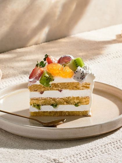The Fresh Fruit Gateau is a light and refreshing option. It has layers of vanilla sponge and fresh cream, topped with a colorful assortment of seasonal fruits like kiwi, orange, and strawberry.