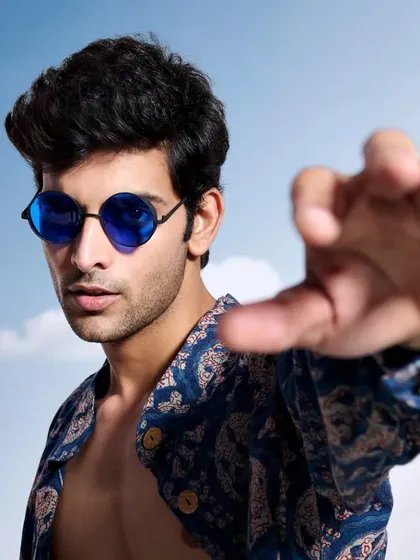 A close-up, engaging shot featuring a block-printed blue shirt. The model's direct gaze and gesture create a connection with the viewer, making the image more impactful for a commercial campaign.