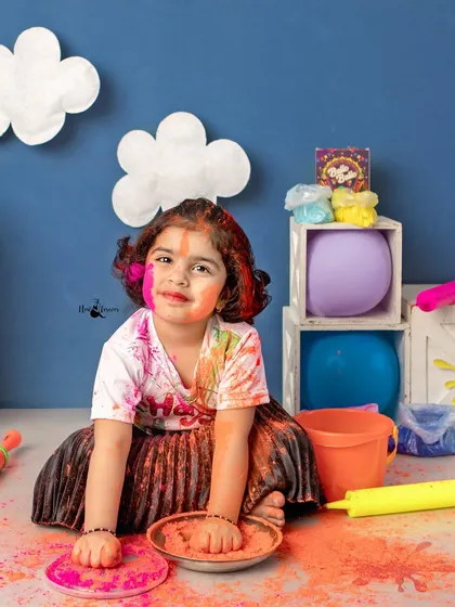 A moment of colorful play. This child is fully engaged with the props during our Holi photoshoot, making for authentic and lively pictures.