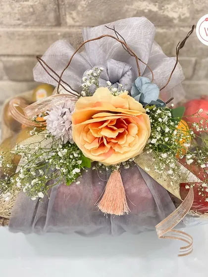 A beautifully wrapped fruit basket, using grey organza and a large peach flower to create an elegant and sophisticated look.