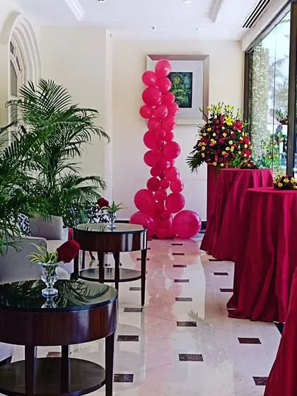 This red balloon column is placed strategically in a hotel lobby to complement the event's color scheme. It demonstrates how a simple balloon stand can effectively enhance the overall decor of a venue.