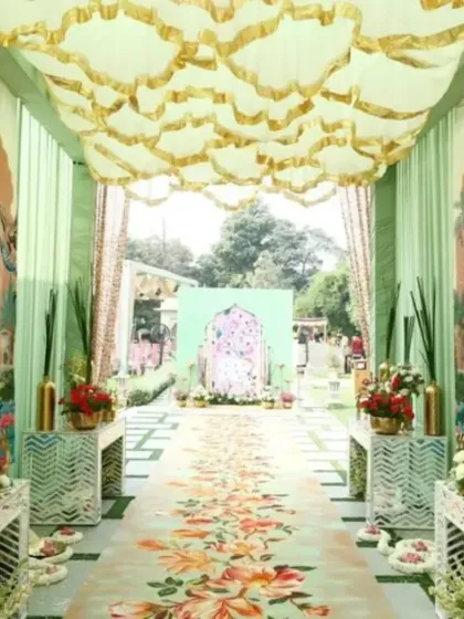 We designed this unique Mehendi entrance walkway inspired by traditional Pichwai art. The decor features a custom-printed floral carpet, pastel green drapes with artistic panels, and a scalloped fabric ceiling, leading to the main event area.