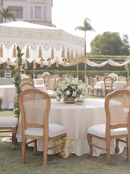 Elegant guest seating with classic wooden chairs and white and gold tasseled canopies. The centerpieces of white lilies and roses add to the sophisticated look.