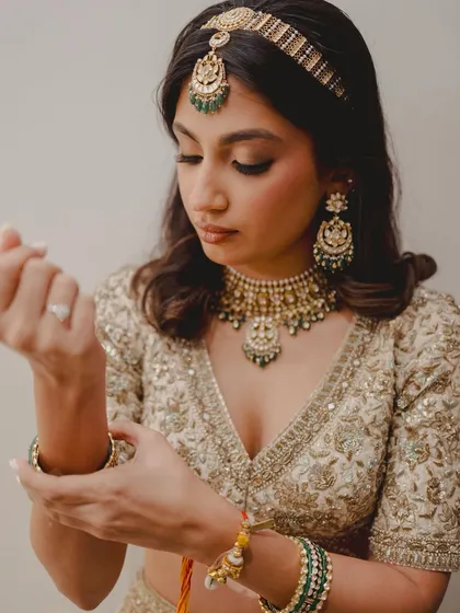 A quiet moment of adjustment. The soft waves in her hair and the delicate embroidery of her ivory lehenga are a perfect match.