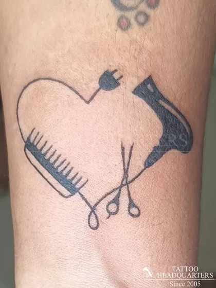 A creative heart-shaped tattoo for a hairstylist, made from a comb, scissors, and a hairdryer.