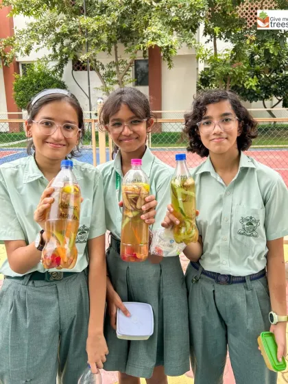 Three students showcase the colorful bio-enzyme mixtures they've created. This activity turns everyday kitchen scraps into a valuable resource for the garden.