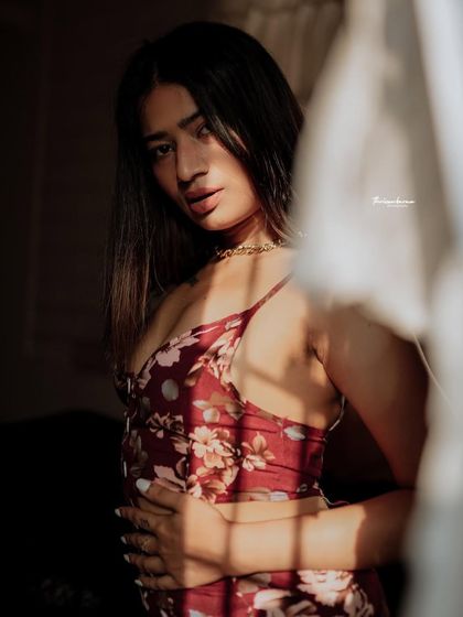 A moody and intimate portrait where the model is partially obscured by curtains, creating a sense of mystery and depth.