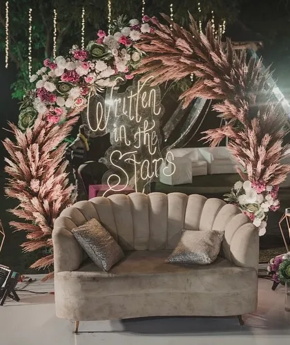 A slightly different angle of the 'Written in the Stars' photo booth, showing the beautiful arch of pampas grass and pink flowers.
