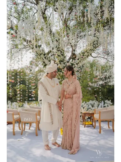 A portrait of pure elegance. The couple shares a quiet moment after their vows, standing under a canopy of white wisteria. Their coordinated pastel outfits and the serene garden setting create a picture of timeless romance.