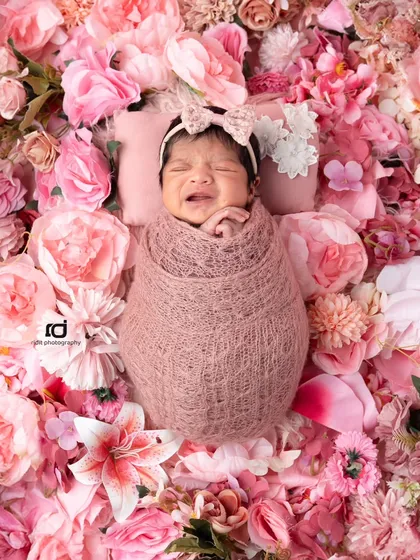 Even a little cry can be a beautiful moment to capture. Surrounded by a bed of pink flowers, this newborn's expression is so real and precious.