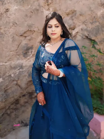 This pose shows the intricate details of her blue engagement lehenga and how the makeup complements the outfit's colors.