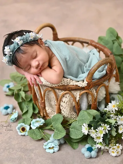 The perfect side-sleeper pose. This classic newborn portrait showcases the baby's delicate features as she naps in a basket adorned with flowers.