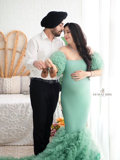 A classic shot that tells a story of anticipation. The couple holds up a tiny pair of baby shoes, their expressions full of hope and excitement for the future.