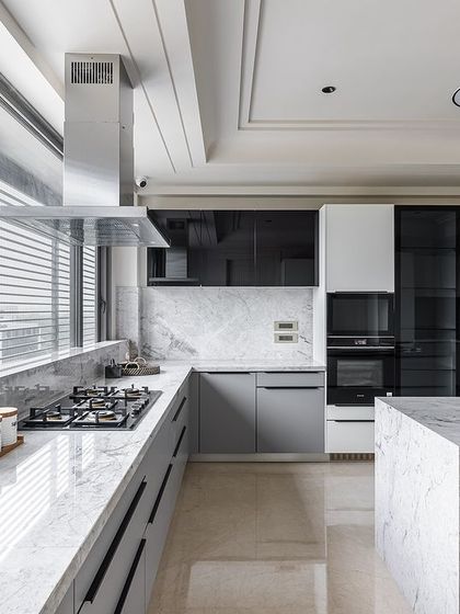 The L-shaped layout and large island provide ample counter space for cooking and entertaining, while large windows ensure the kitchen is filled with natural light.