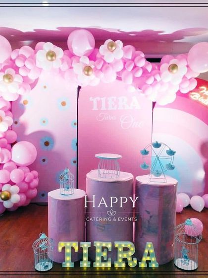Another view of the pink-themed party setup, showing the "TIERA" marquee lights and decorative props like a mini Ferris wheel and bird cages.