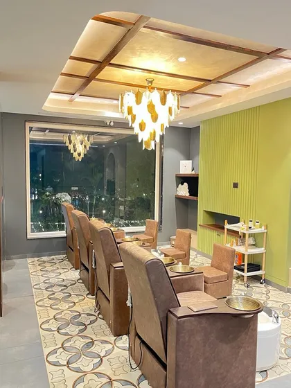 The pedicure and relaxation area at Madonna Salon, designed for ultimate comfort. Plush reclining chairs face a large window, while a statement chandelier and patterned floor tiles add a touch of glamour to the space.