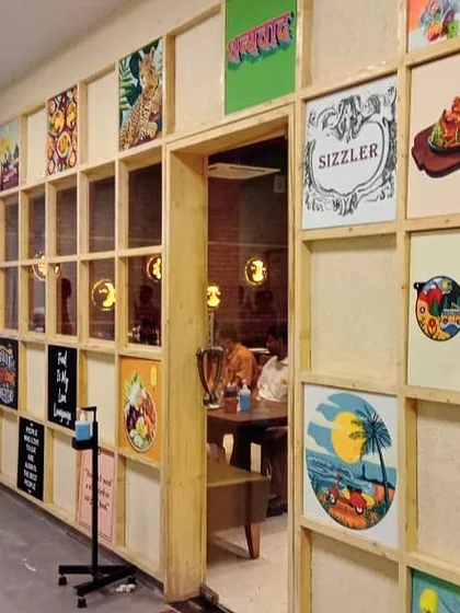 The Yoko Sizzlers entrance partway through the installation, with various food-themed and branded paintings being placed into the grid.