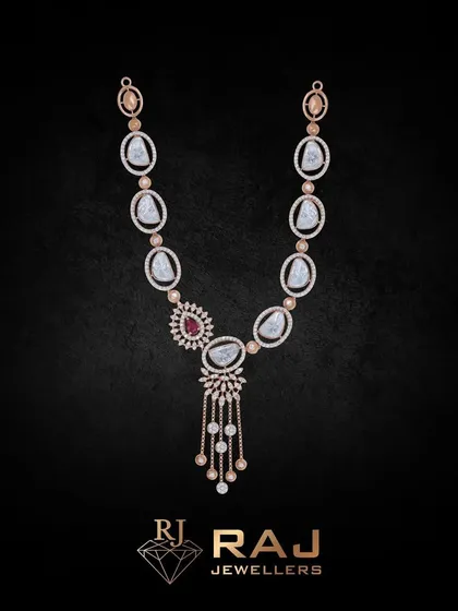 This long necklace, or 'haar,' features large, uncut-style stones interspersed with smaller red gems and CZ tassels. It is a grand, opulent piece perfect for layering or wearing as a standalone statement.