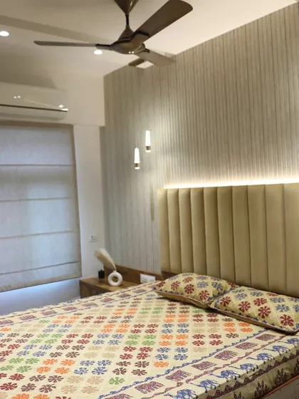 This modern bedroom features a bed with a tall, vertically-paneled headboard and stylish hanging lights. The fluted wall texture adds a contemporary and sophisticated feel.