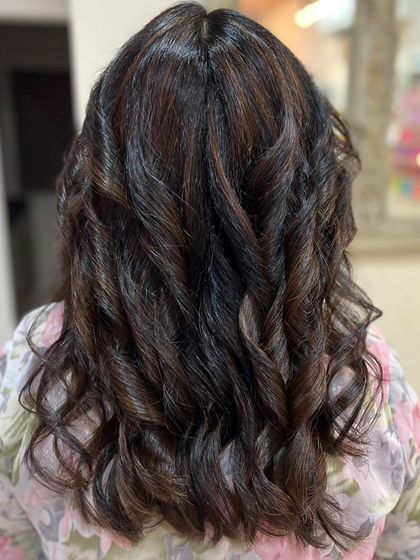Elevating a classic brunette with chic brown highlights. The tight curls in this style showcase the contrast and dimension of the color work, proving that even subtle changes can make a big impact.