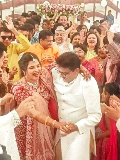 The bride and groom surrounded by family and friends during a joyous moment at their musical wedding. The live lagnageet in the background adds to the festive atmosphere.