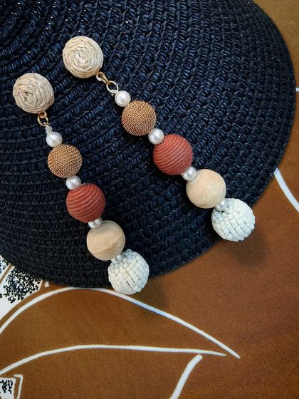 These raffia-wrapped round pompom earrings are a playful and unique addition to any jewellery collection.