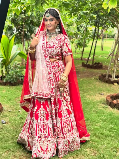A full view of a classic royal bride in a stunning red lehenga. I provide complete styling, including professional lehenga draping, to ensure every detail is perfect. This look is designed to be grand yet feel comfortable, allowing you to enjoy your day to the fullest.