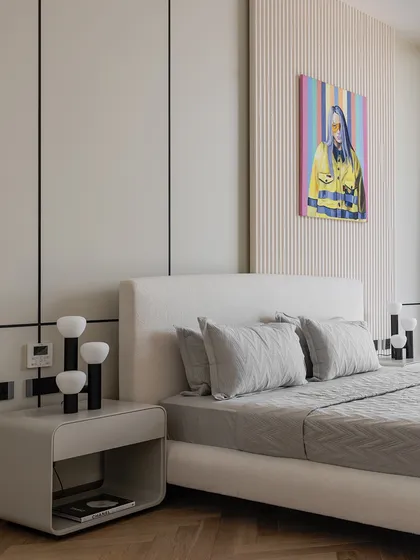 In this modern bedroom, we used a calm, neutral palette and clean lines to create a serene atmosphere. A fluted feature wall adds texture behind the bed, while a vibrant piece of modern art provides a bold pop of color.