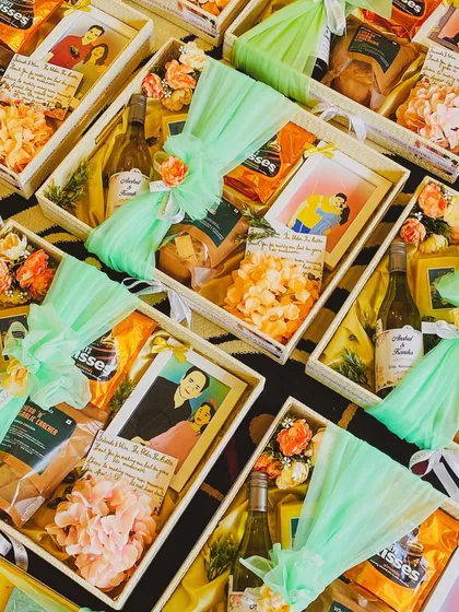 A top-down view of a large order of custom welcome hampers ready for a wedding event. Each basket is consistently styled with a mint green theme, including wine, snacks, and a personalized photo frame, showcasing my ability to handle bulk orders with a personal touch.
