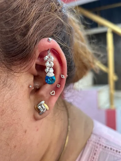 A bold and colorful ear stack featuring a large blue topaz hanging, surrounded by a constellation of smaller studs.