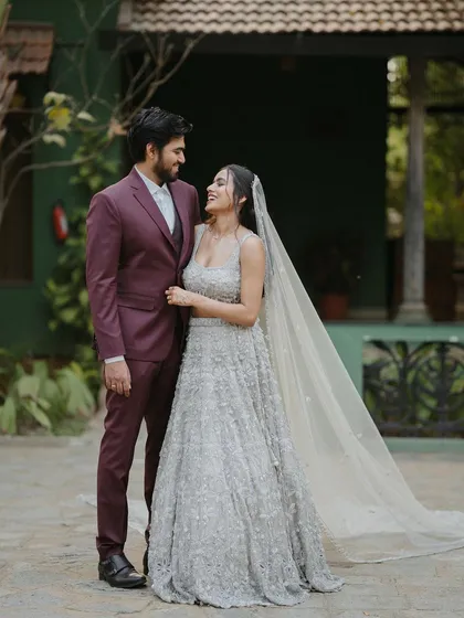 A modern couple, the bride in a stunning silver lehenga, shares a happy moment in the courtyard.