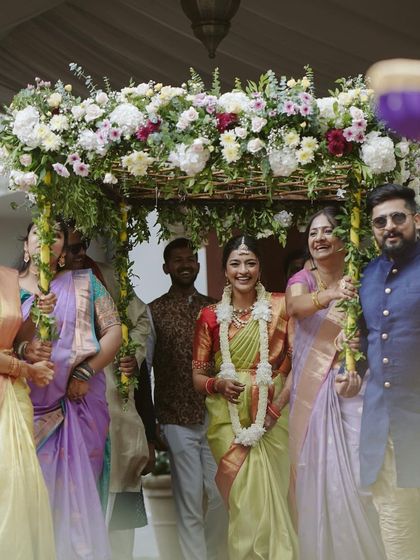 The bride makes her entrance under a beautiful 'phoolon ki chadar' made of fresh white and pink flowers, a truly magical moment.