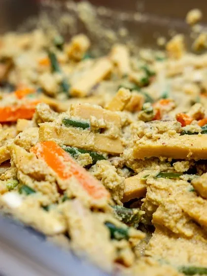 A close-up of a vegetable dish being prepared for an Onam sadhya. The colors are vibrant, and the shot conveys a sense of abundance and freshness.
