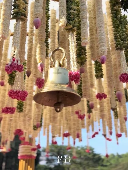 A close-up of the handcrafted details on the pink paradise mandap. Traditional temple bells were hung amidst thousands of tuberose and lotus garlands, adding a gentle, melodic sound to the ceremony.