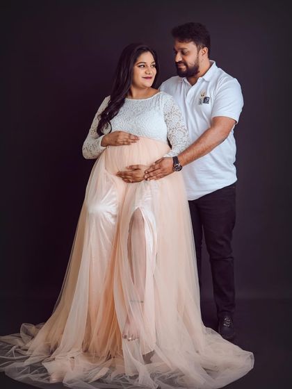 A lovely pose that showcases the sheer, flowing skirt of the maternity gown while capturing the partner's loving embrace.