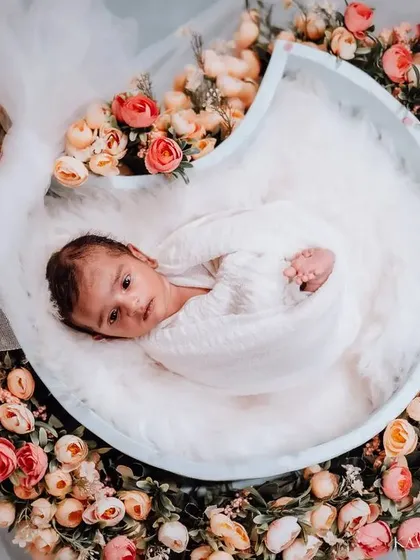 A wide-angle view of the floral moon setup. This shows the full arrangement with the tulle bow, highlighting the artistry and detail that goes into each themed newborn shoot.