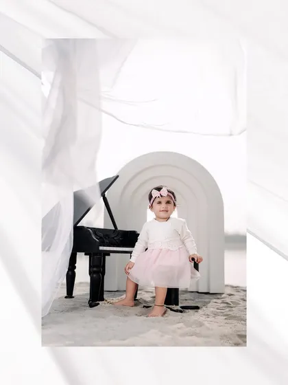 A serene musical moment on the sand. This little girl looks like a tiny virtuoso, sitting at her piano against a calm, waterside backdrop.