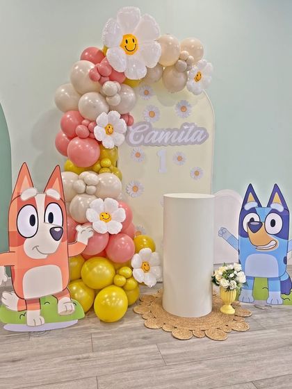 An adorable Bluey and Bingo themed setup for a first birthday. This decoration uses pastel-colored balloons and daisy accents for a softer, sweeter take on the popular cartoon theme.