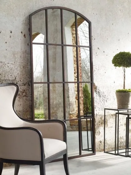 This grand, arched window-pane mirror serves as a stunning architectural feature in this living space. We crafted it to create an illusion of space and light, using a rustic metal frame for a classic, industrial-loft feel. We build large-scale statement mirrors to your exact dimensions.